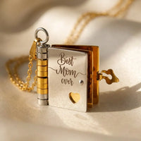 Macro detail of Best Mom Ever engraving on silver 
and gold book locket pendant with heart cutout — 
heartfelt mother daughter keepsake jewelry