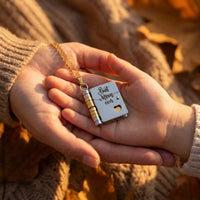Mother and daughter hands holding Best Mom Ever 
book locket necklace in autumn light — emotional 
mother daughter bond jewelry
