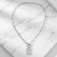 Carried By Faith silver cross necklace flat lay on marble