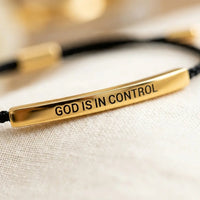 Macro detail of God Is In Control gold engraved 
plate on faith bracelet — premium Christian 
jewelry close-up