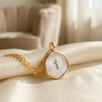 Golden cross pendant close-up detail mother of pearl 
center with engraved cross and 14K gold frame