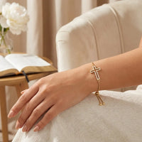 Woman wearing gold hollowed out cross bracelet with crystal pavé 14K gold faith jewelry