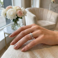 Woman wearing silver three-band interlocked fidget ring on hand resting on cream linen luxury home setting