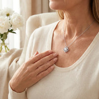Elegant mother wearing silver love knot necklace pendant 
on collarbone cream sweater lifestyle